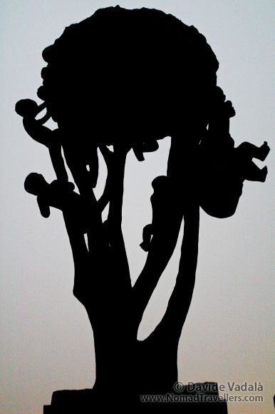 The silhouette at night of a statue of kids climbing a tree in Vigeland park, Oslo