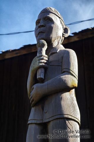 A modern Dayak Hampatong wooden pole sculpture in front of Benung Longhouse