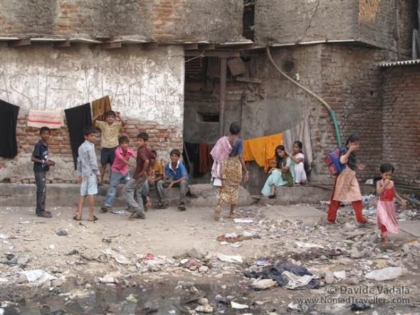 Life is going on and kids gather and play where there is an opening of space and light. Girls comb each other's hair, a common habit in India. 045 Mumbai-Bombay-Dharavi-Slum India 3925
